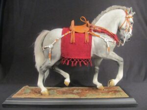 A statue of a grey horse with a red saddle, resembling a Celtic cavalry steed.