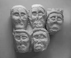 Five Celtic stone faces on a wall.