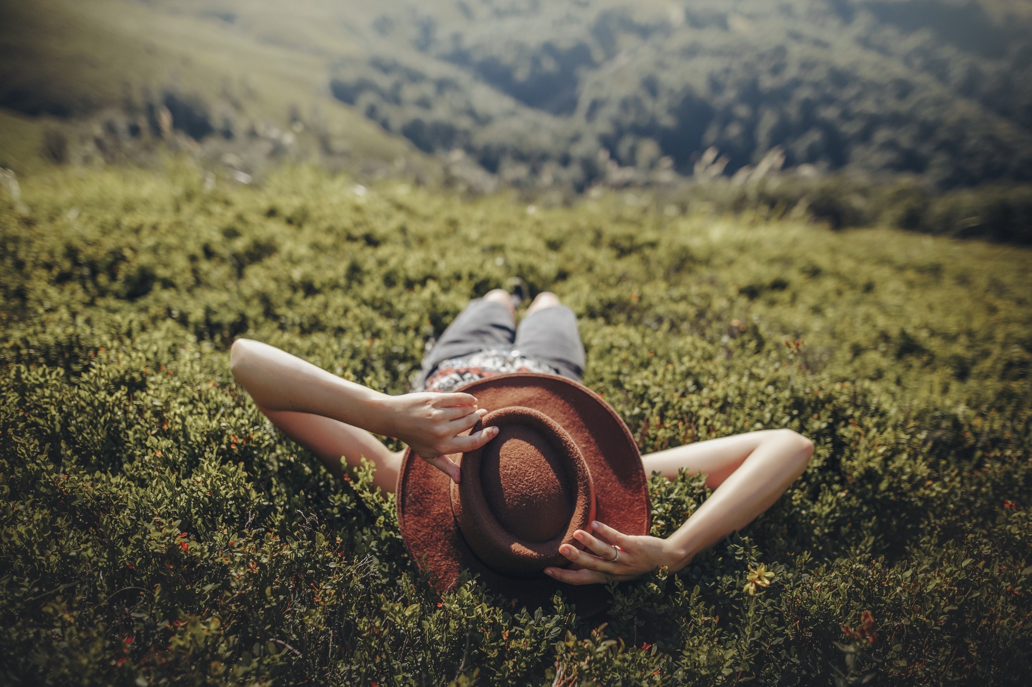 A woman alying in the grass and looking at the sky to reflect and celebrate Beltane.