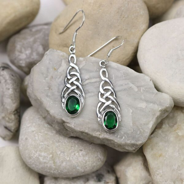 A pair of sterling silver earrings with emerald stones.
