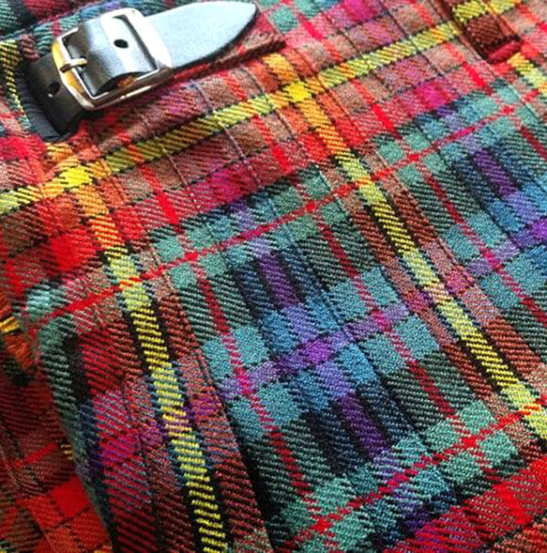 A close up of a plaid skirt with a belt, featuring Pride Tartan neck tie accents.