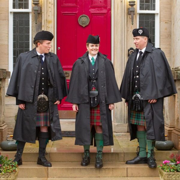 Three men wearing Bandspec Inverness Rain Capes and standing in front of a red door.