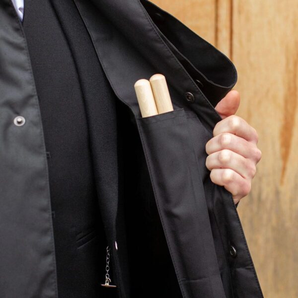 A man in a Bandspec Inverness rain cape with a pair of wooden sticks in his pocket.