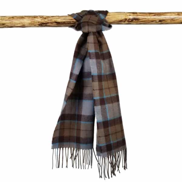 A brown and blue plaid Tartan Scarf - OUTLANDER Lambswool with fringe hanging on a wooden rod.