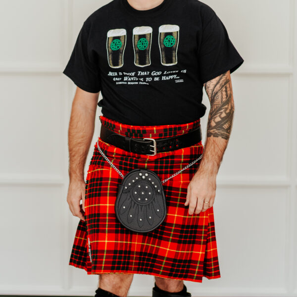 Person wearing a red tartan kilt, black t-shirt with three green beer mugs, and a Celtic Knot Utility Belt and Buckle, standing against a light background.