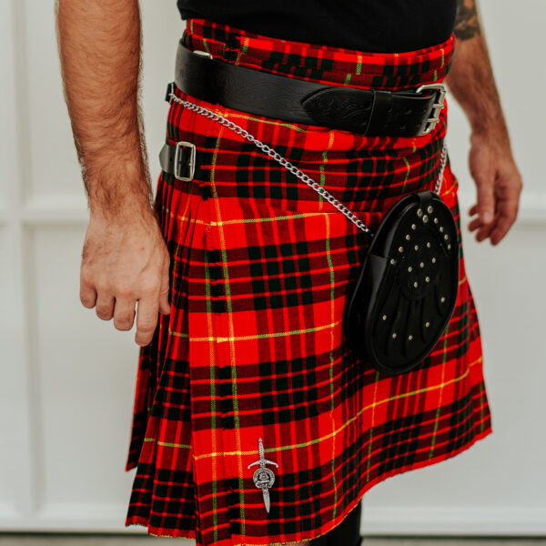 A person is shown from the torso down wearing a red and green plaid kilt with a black sporran and a nice leather belt adorned with the Celtic Knot Utility Belt and Buckle.