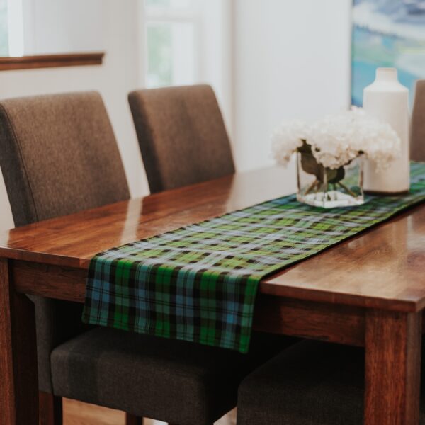 A green and blue tartan table runner on a wooden table.