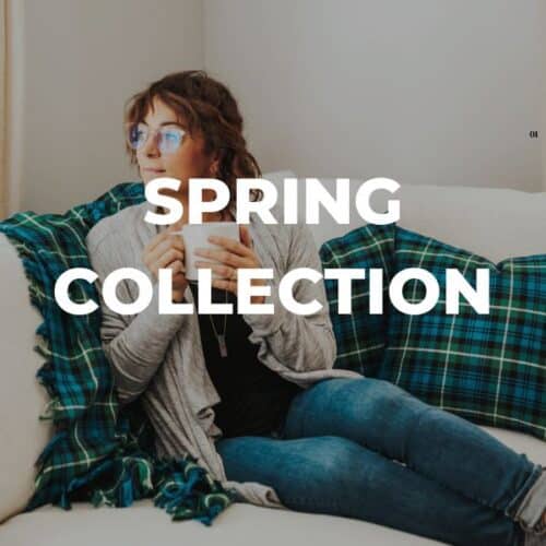 A woman sitting on a couch, browsing through shopping guides for the spring collection.