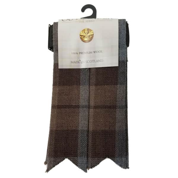 A woolen scarf in shades of brown and grey is displayed on a black hook, labeled "100% Outlander Premium Wool Tartan Flashes" and "Made in Scotland.
