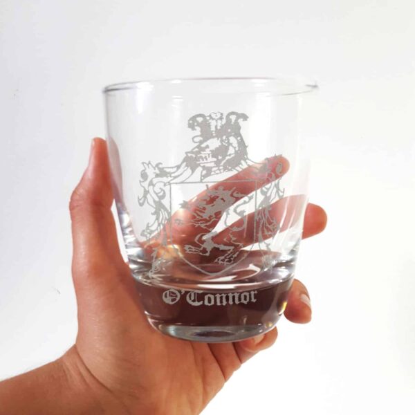 A person holding up an Irish Coat of Arms 23.75oz Decanter and Whisky Glass Set with a crest on it.