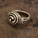 A Triskele Ring with a spiral design on it.