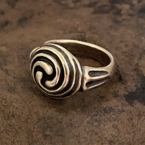 A Triskele Ring with a spiral design on it.