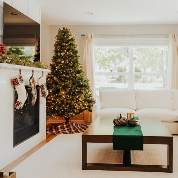 A living room adorned with a Christmas tree and stockings, featuring the Stewart Dress/MacKenzie Tartan Mantel Runner - Homespun Wool Blend for a cozy and homely ambiance.