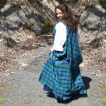 A woman wearing a green and blue tartan kilt made of Welsh Tartan Earasaid - 13oz Medium Weight Premium Wool.