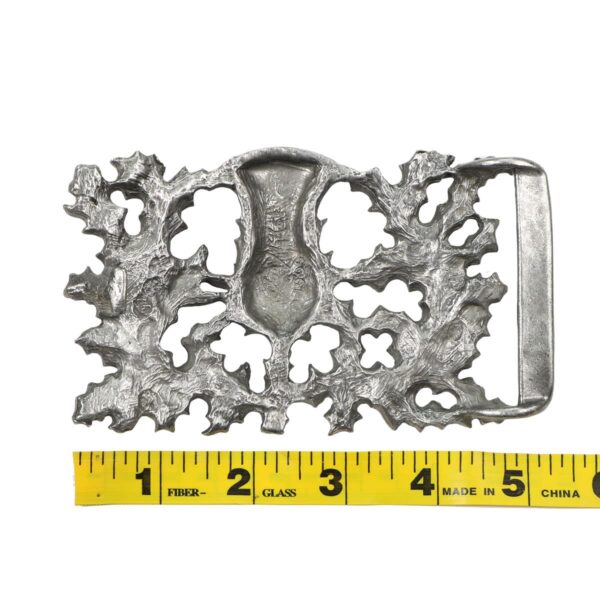 A Don McKee Thistle Kilt Belt Buckle with a measuring tape.