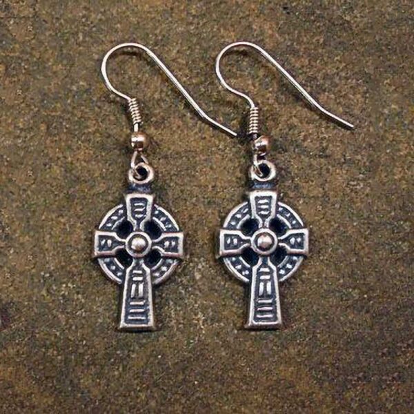 A pair of Celtic Cross Earrings delicately placed on a stone surface.