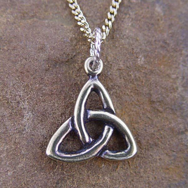 A sterling silver Triquetra Pendant on a stone.