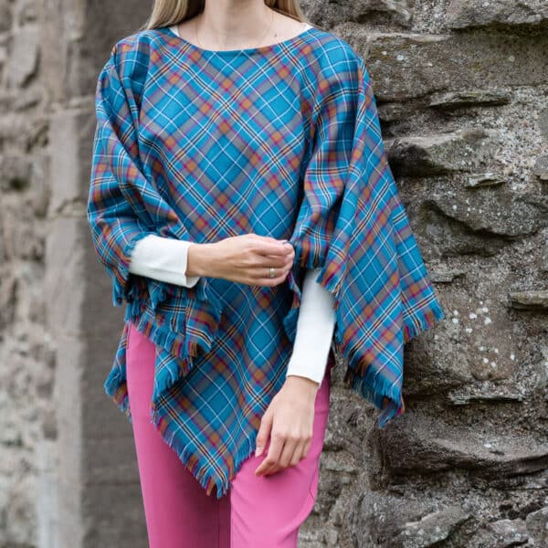 A woman wearing a Light Weight 11oz Premium Wool Tartan Poncho made of light weight premium wool.