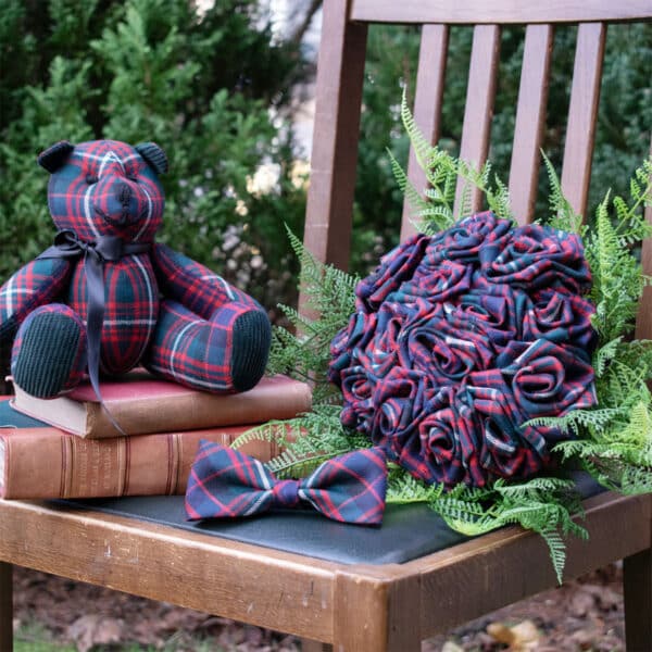 The Light Weight 11oz Premium Wool Tartan Rose Bouquet sits on a chair next to a bouquet of flowers. The Light Weight 11oz Premium Wool Tartan Rose Bouquet is made of premium wool tartan and features light-weight corsages.