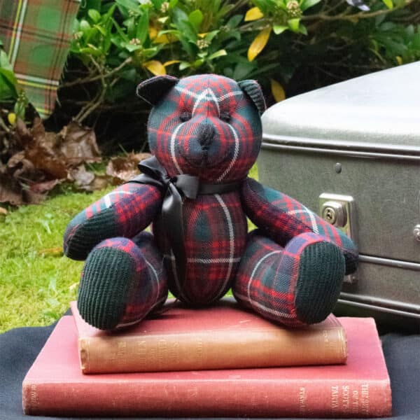 A Light Weight 11oz Premium Wool Tartan Bear sitting on top of a lightweight suitcase.