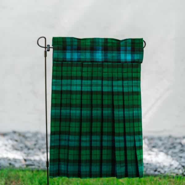 A Black Watch Ancient Tartan Kilted Garden Flag - Homespun Wool Blend, showcasing a classic green and black plaid pattern, elegantly hanging on a pole.