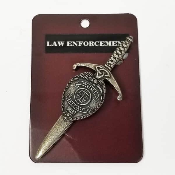 A Law Enforcement Kilt Pin shaped like a sword with intricate designs, displayed on a dark background with the text "law enforcement" above.