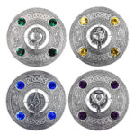 Four elaborate Crest and Gem Plaid Brooches feature intricate Celtic designs, each embellished with six vibrant gemstones. Every brooch showcases a distinct central emblem, including a lion, a unicorn, a dragon, and a thistle.