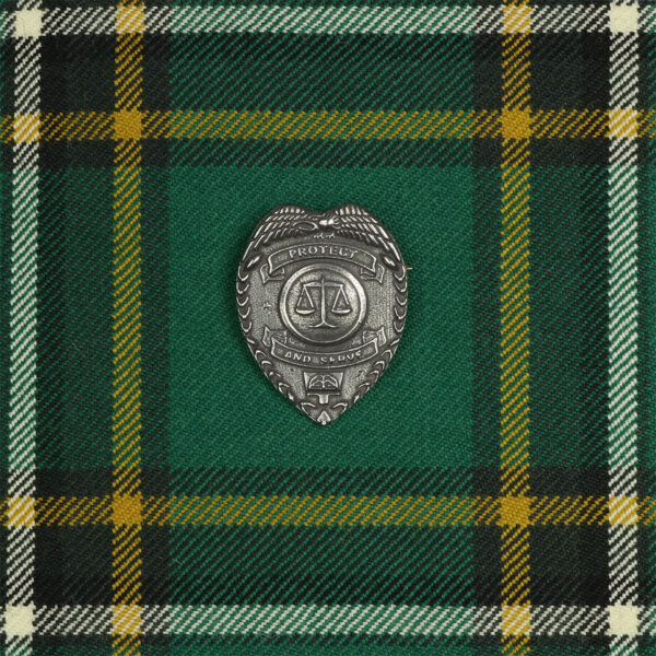 A Protect and Serve Law Enforcement Cap Badge on a green tartan.
