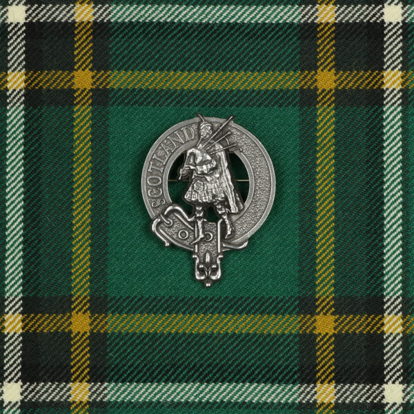 A Scottish claddagh crest badge on a green tartan, complemented with a Scottish Piper Cap Badge/Brooch.
