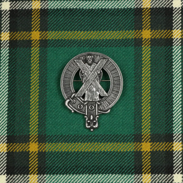 A green and yellow tartan Saint Andrew's Cross cap badge/brooch on a green background.