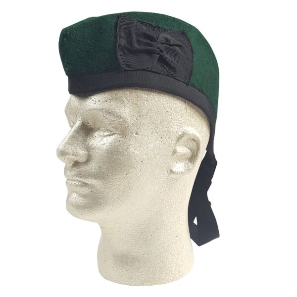 A mannequin wearing a green cap with a black Felted Wool Glengarry bow.