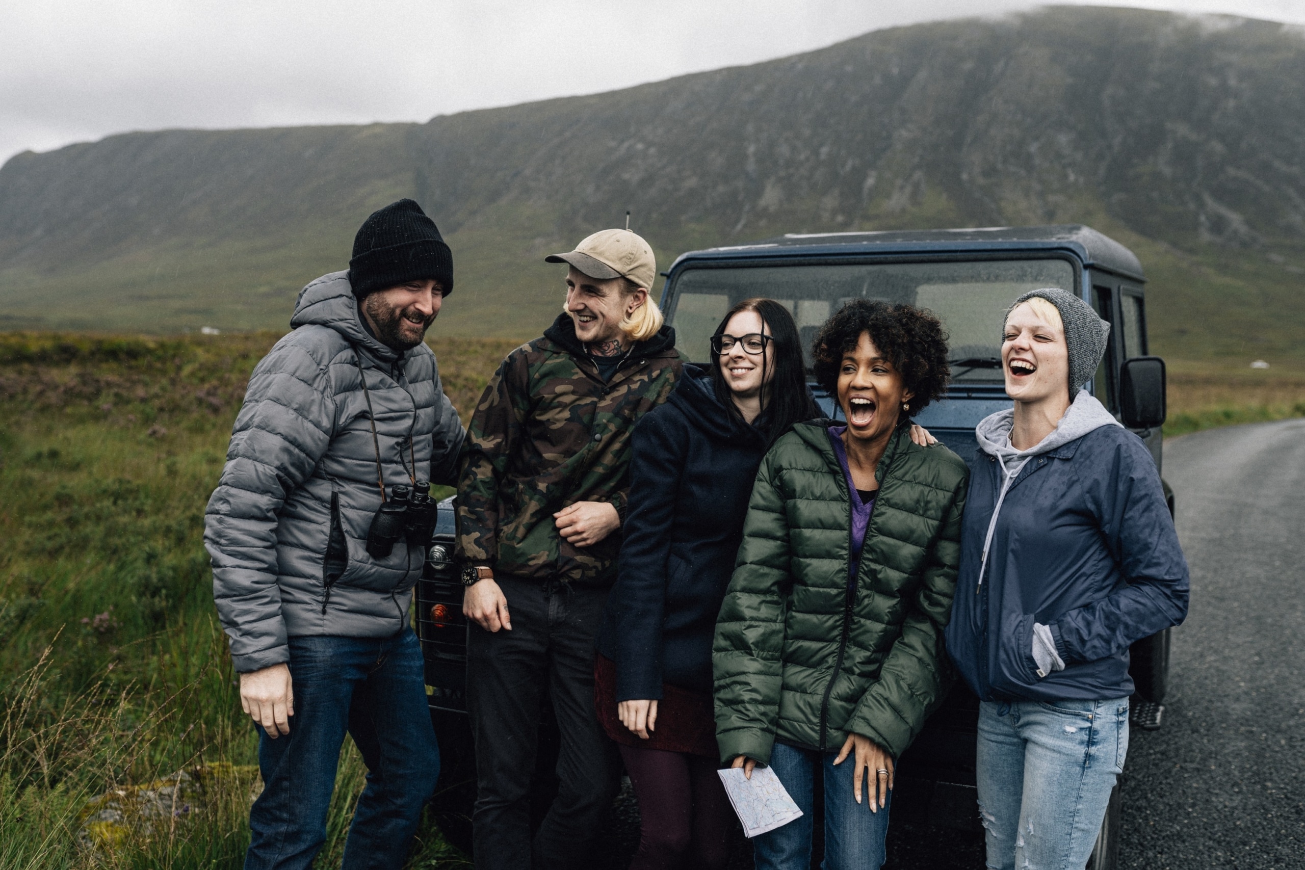 A group of friends taking a break from driving in Scotland, laughing and using Scottish slang