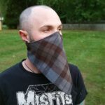A man wearing a Tartan Bandana Masks - Cotton 80/20 in the grass.
