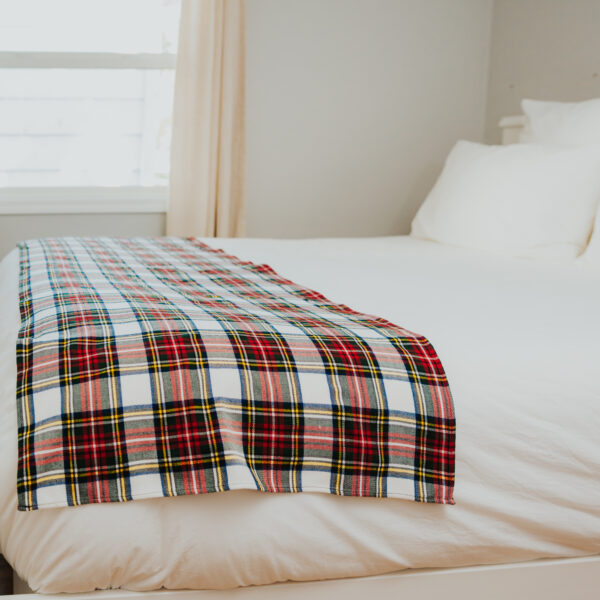 A Homespun Tartan Blanket/Throw on a bed.