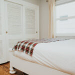 A white bed with a Homespun Tartan Blanket/Throw on it.