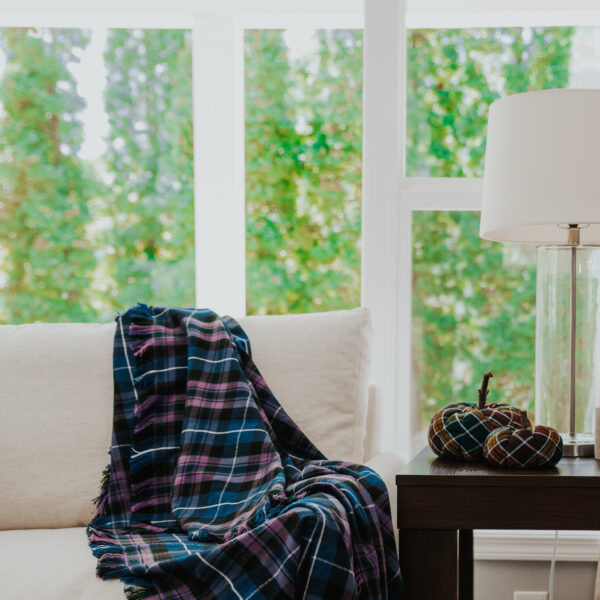 A Homespun Tartan Blanket/Throw on a couch next to a window.