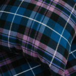 A close up of a Homespun Tartan Blanket/Throw, reminiscent of homespun tartan blankets, adorning a bed.