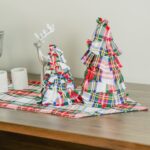 Two Tartan Christmas Trees - Homespun Wool-Blend on a wooden table.