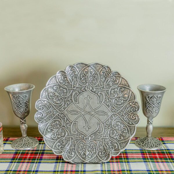 A silver plate and two silver goblets on a plaid tablecloth, with a Tartan Scarf - 13oz Premium Wool draped elegantly nearby.