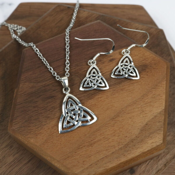 A Trinity Knot Set - a silver necklace and earrings - displayed on a wooden surface.
