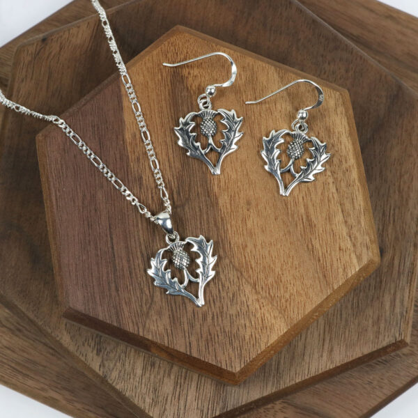 A Scottish Thistle Necklace set on a wooden table.