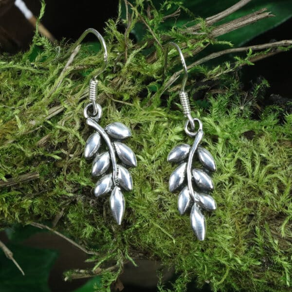 A pair of Tree of Life Earrings on moss.