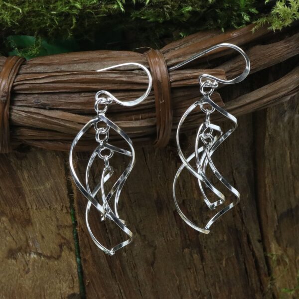 A pair of silver Tree of Life Earrings on a wooden board.