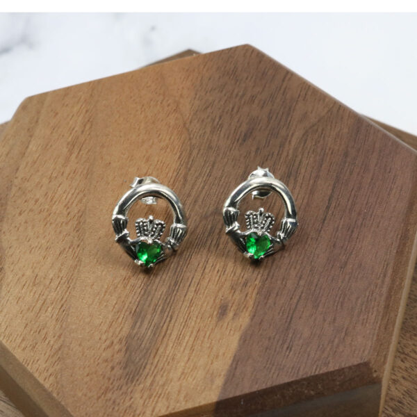 A pair of claddagh earrings with emerald stones, featuring Triquetra Sterling Silver Earrings.
