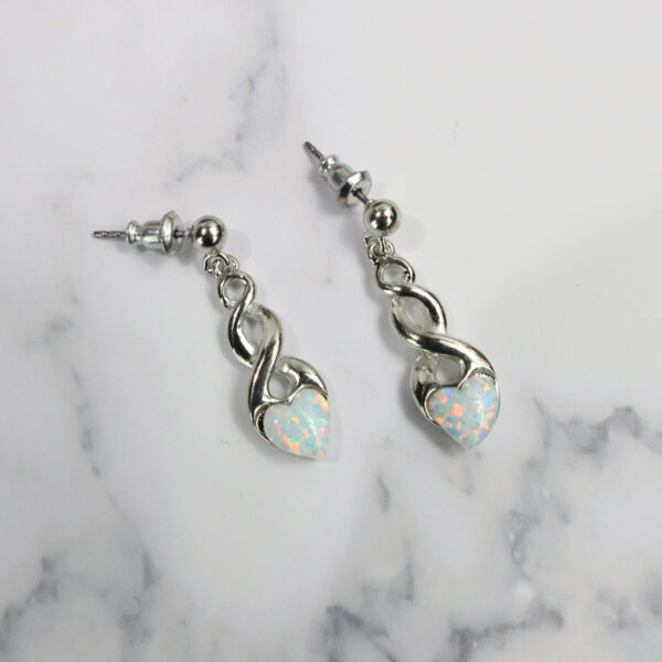 A pair of opal heart earrings adorned with Triquetra Sterling Silver Earrings on a marble surface.