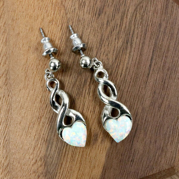 Opal Heart Earrings on a wooden table.