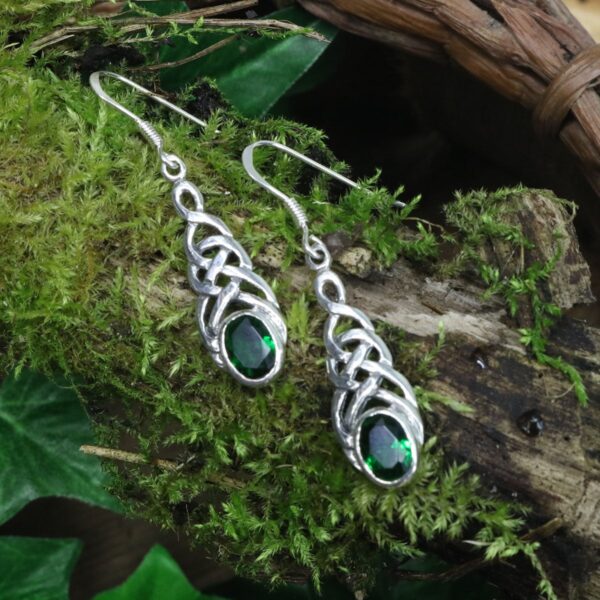 A pair of sterling silver Tree of Life Earrings with green emeralds, featuring a tree of life design.