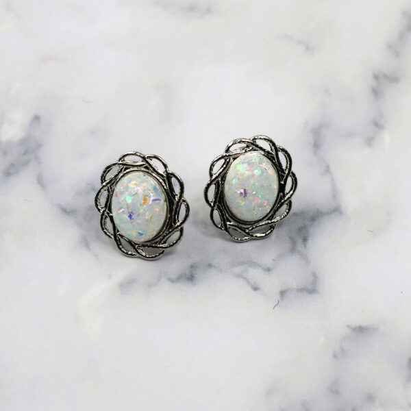 A pair of Opal Knot stud earrings on a marble surface.