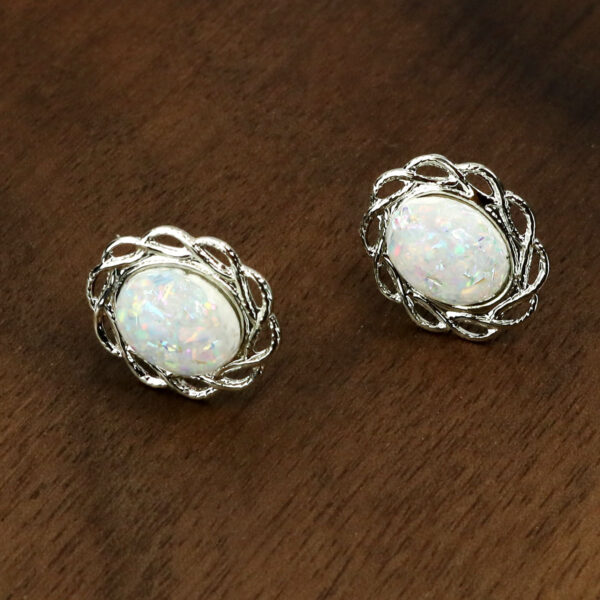 A pair of white Opal Knot stud earrings on a table.