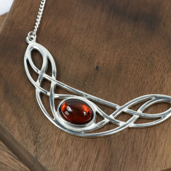 An Amethyst Celtic Knot necklace adorned with a silver pendant and a captivating amber stone.